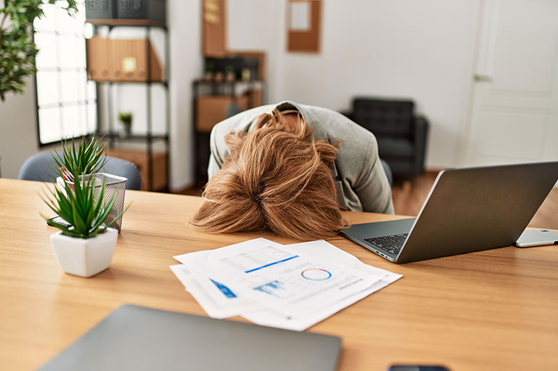 Mental-wellbeing-person-with-head-on-table Person with head on table frustrated by noise pollution.